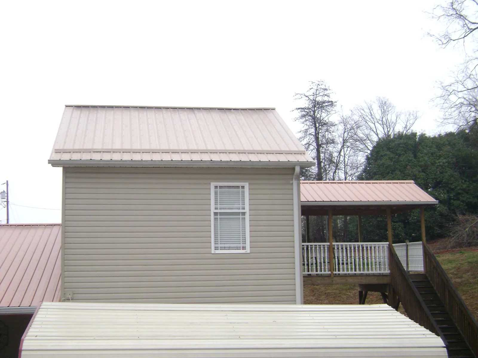Tan metal roofs on a two story addition and attached porch, from a Roof Replacement job in Belvedere Tiburon