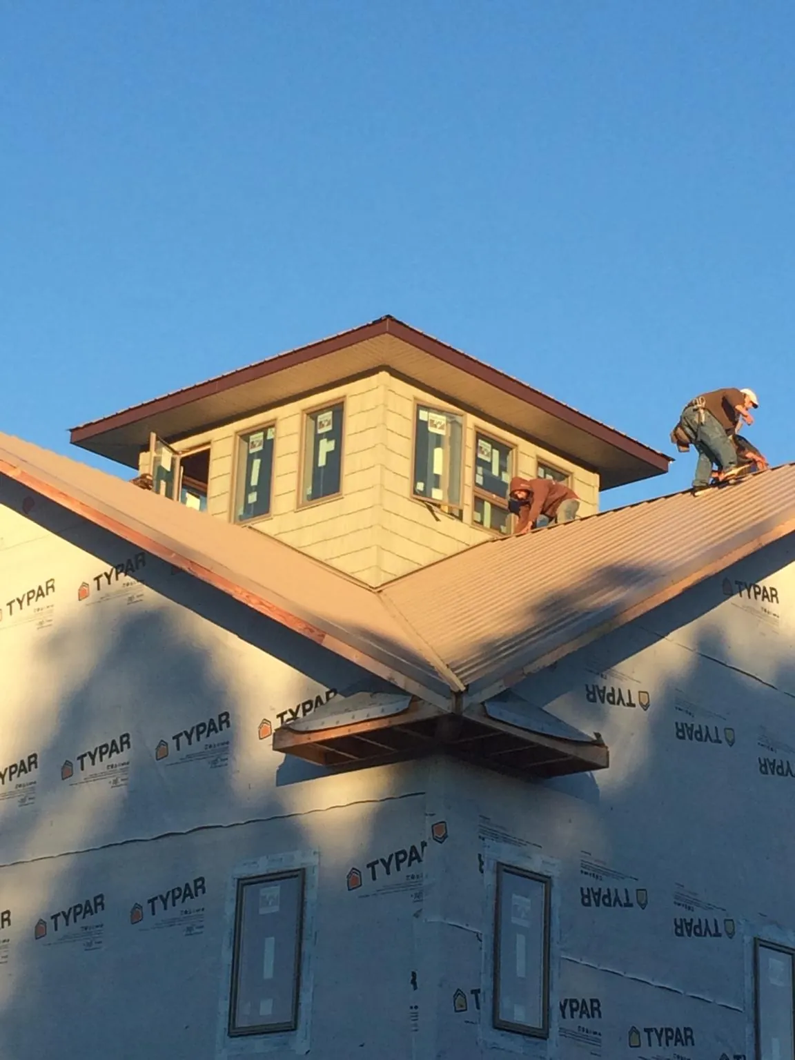 Roofers working around a rooftop cupola on a new metal roof at sunset — Roof Waterproofing in Belvedere Tiburon by Roofing Brothers